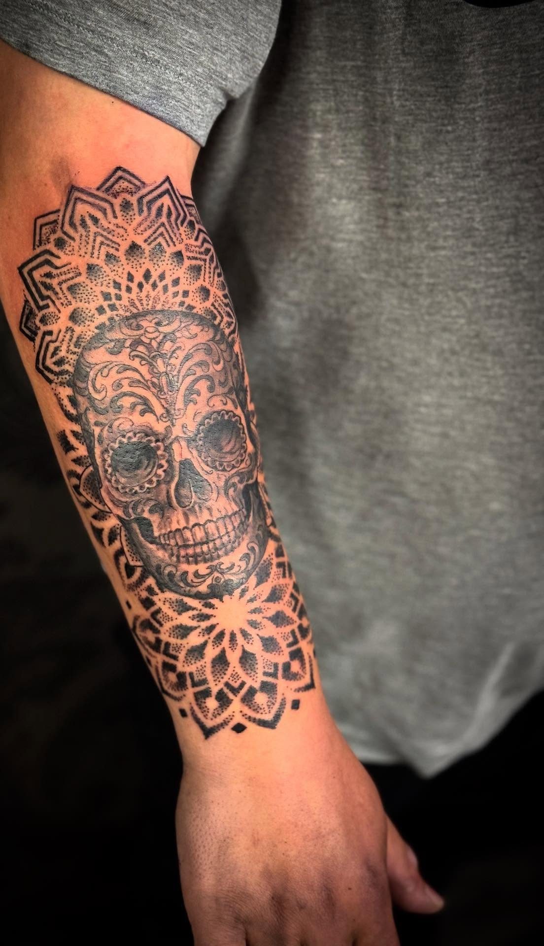 Sugar skull tattoo with mandala patterns on a person's forearm
