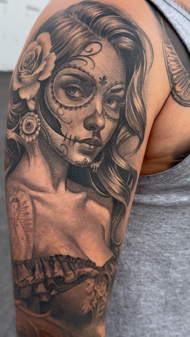 Woman face sugar skull tattoo with a rose on a person's upper arm