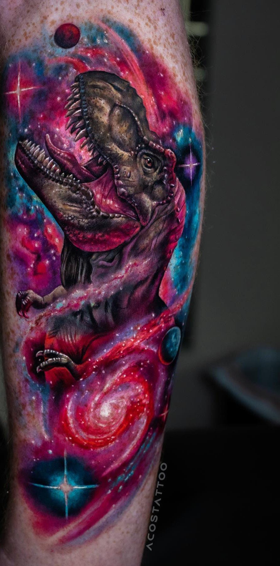 T-Rex tattoo on an arm surrounded by colorful cosmic nebulae and stars