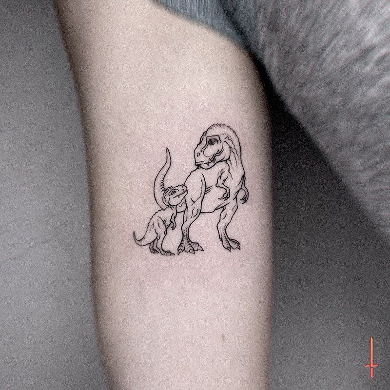 T-Rex and baby dinosaur line-art tattoo on a person's pale skin