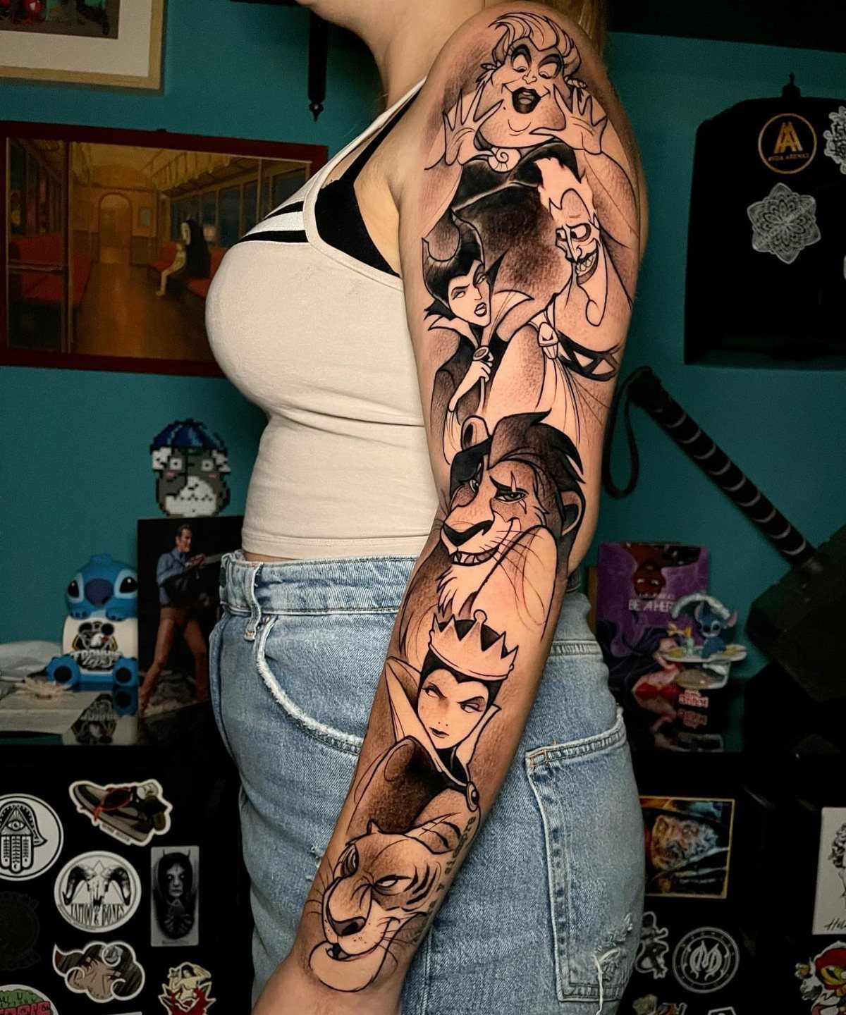 Arm sleeve tattoo featuring various Disney villains in black and grey ink.