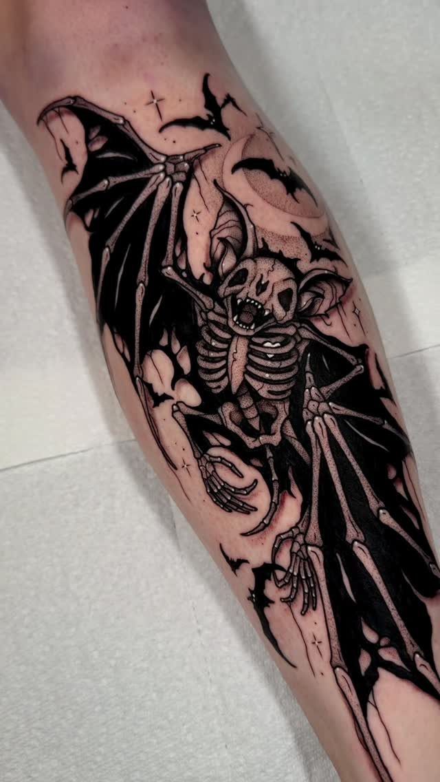 Skeletal bat tattoo on an arm with bony wings and a crescent moon.