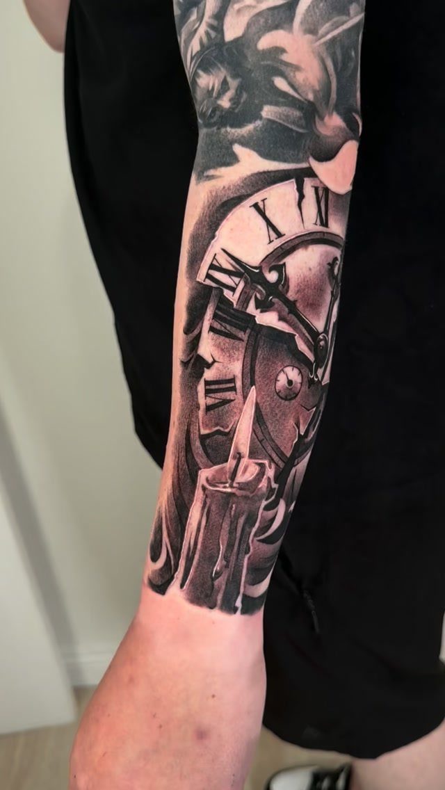 Broken clock tattoo with Roman numerals and a candle on a forearm.
