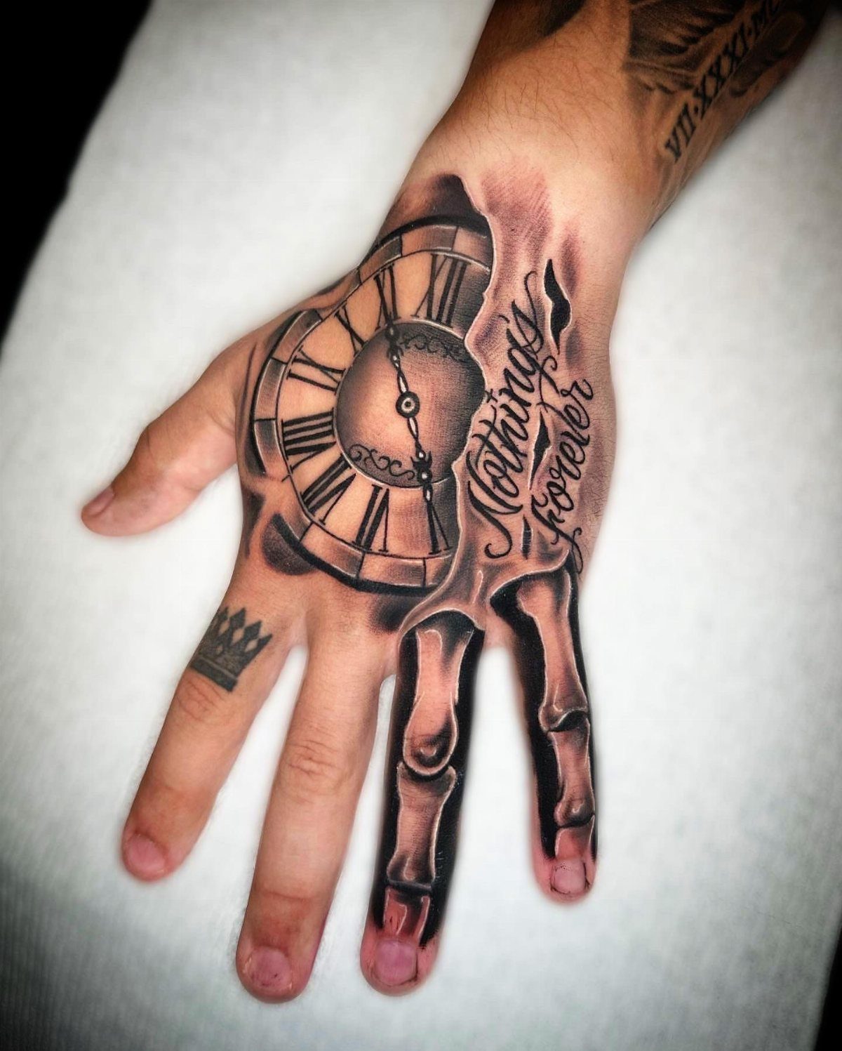 Clock tattoo on a hand with Roman numerals and anatomical finger bones.