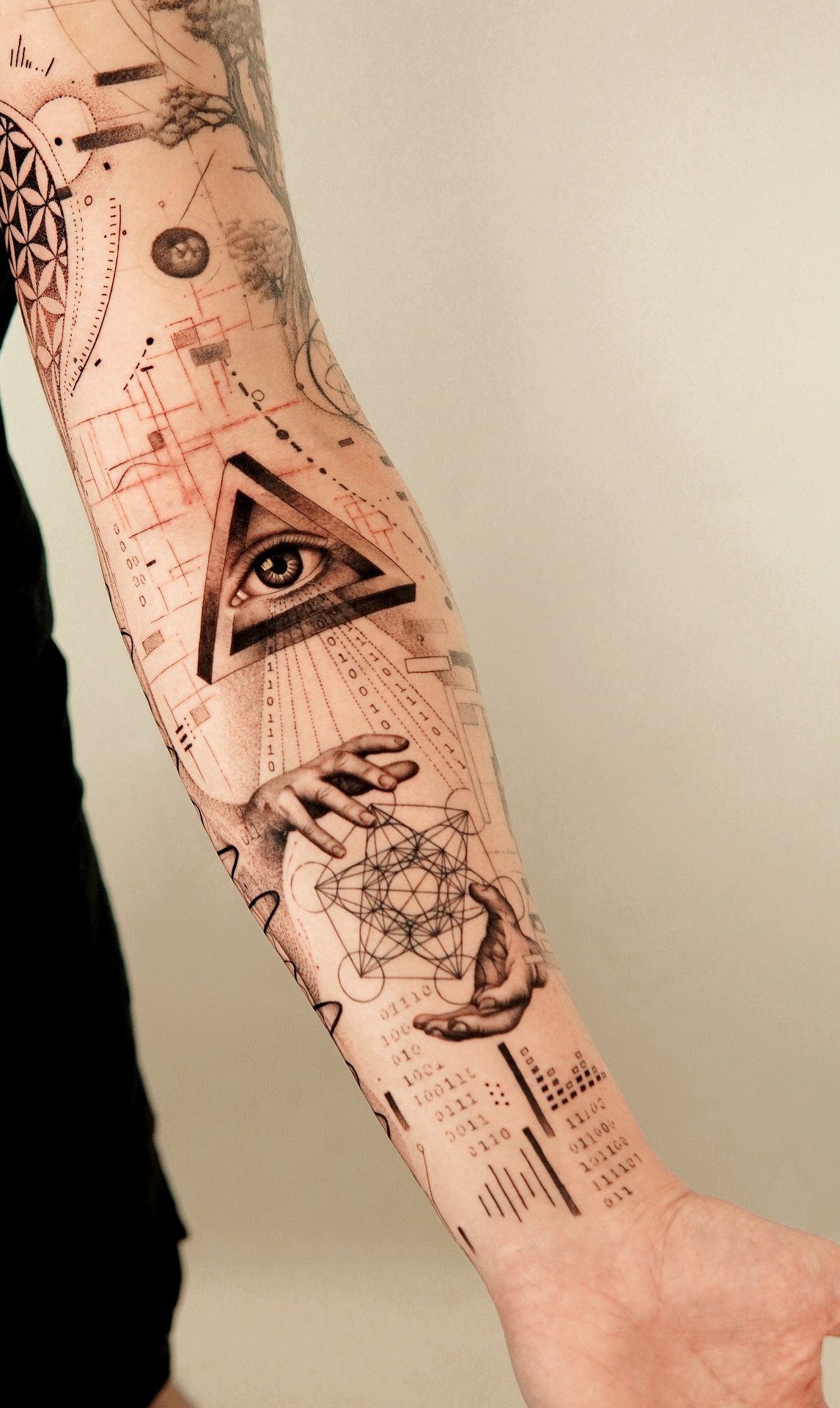 Geometric eye tattoo on an arm featuring a triangle and complex mathematical shapes.