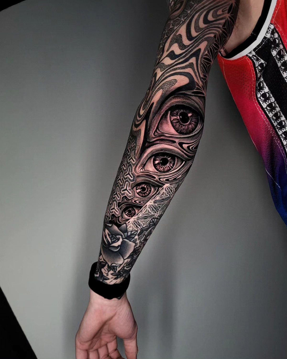 Surreal eye tattoo on a forearm with melting patterns and a rose.