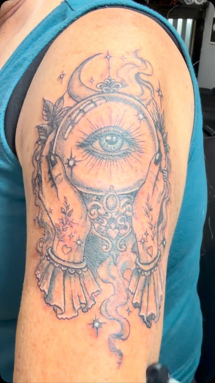 Tattoo of a mystical eye in a crystal ball held by two hands.