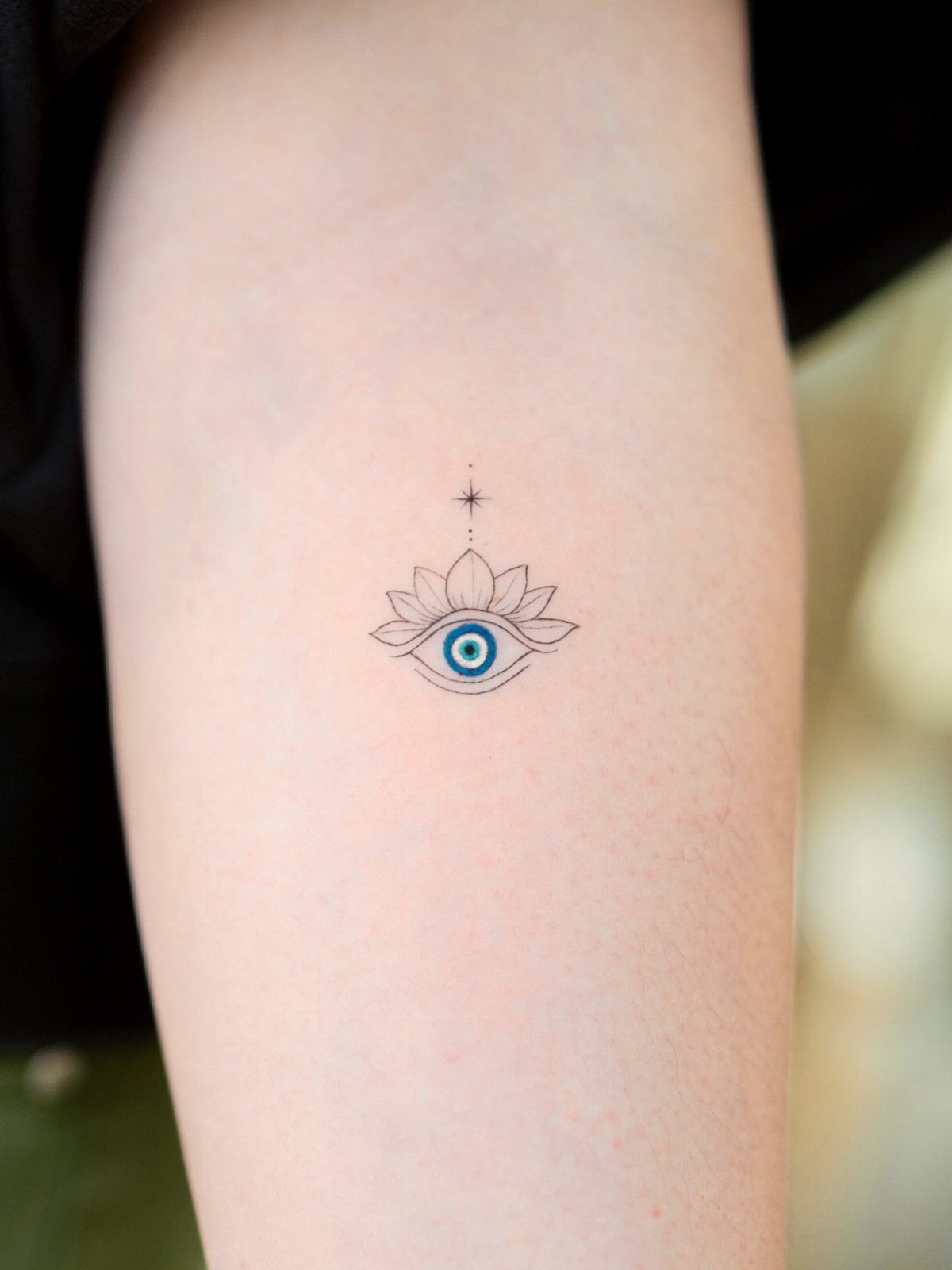 Third eye tattoo with a blue iris and lotus flower on an arm