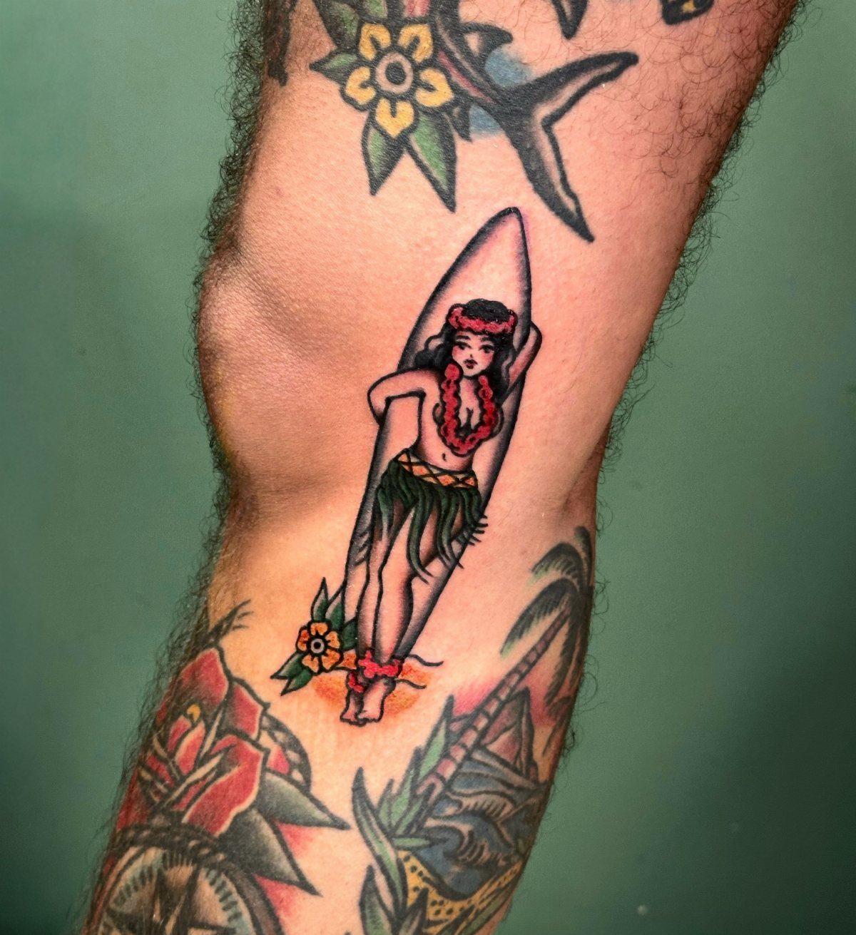 Hula girl tattoo with a surfboard on a person's leg in traditional style