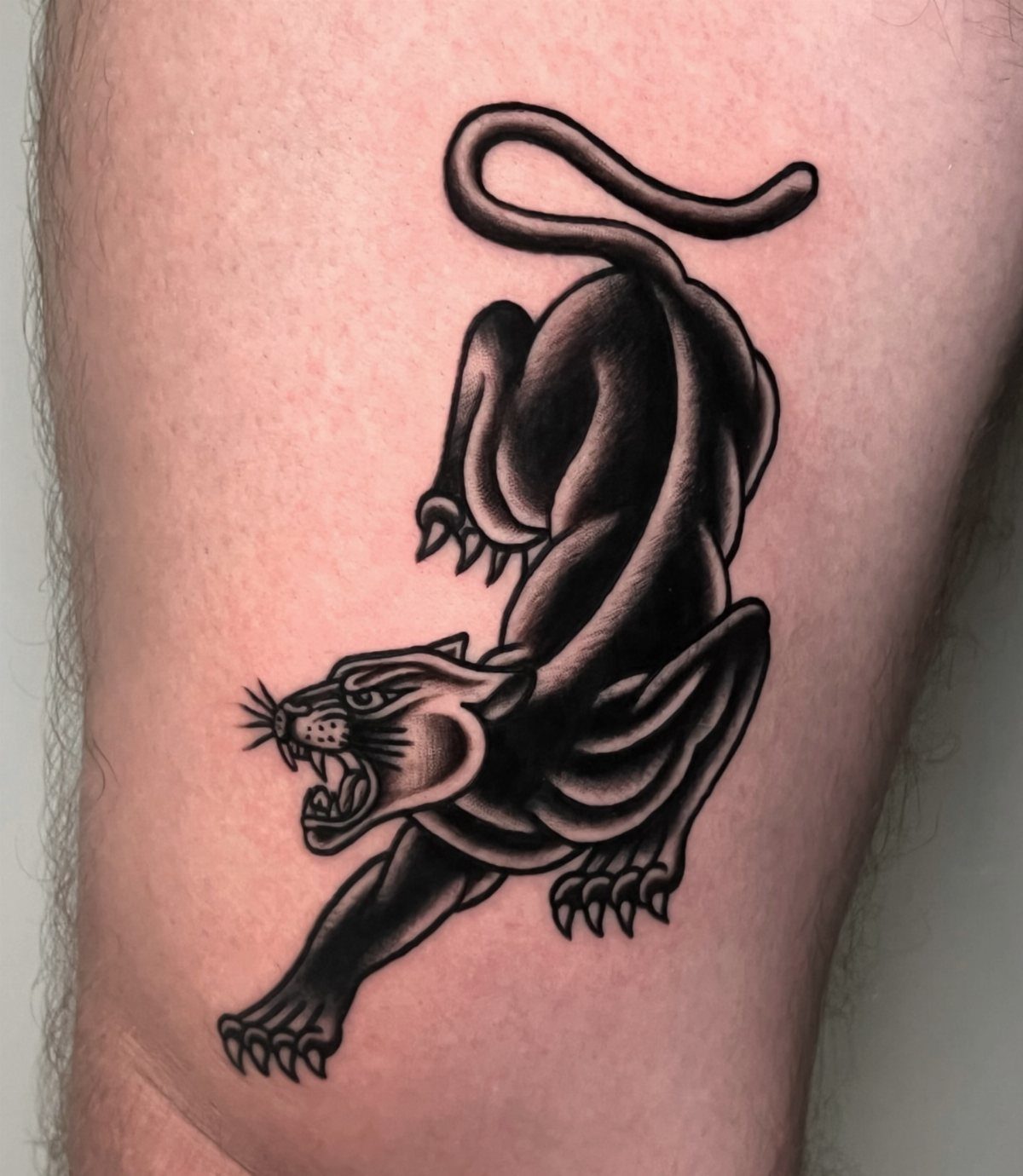 Traditional black ink panther tattoo on skin with bold outlines and shading.