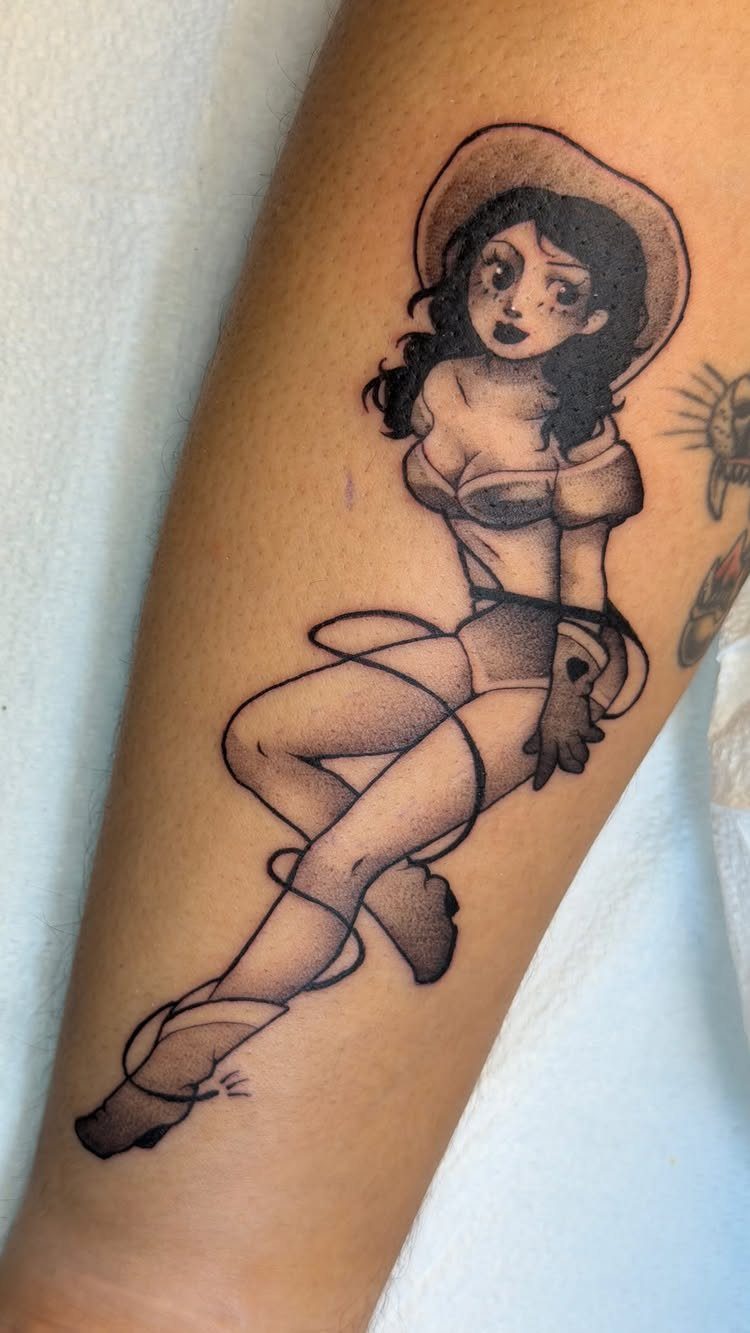 Pin-up girl tattoo with a wide hat and white top on a forearm.