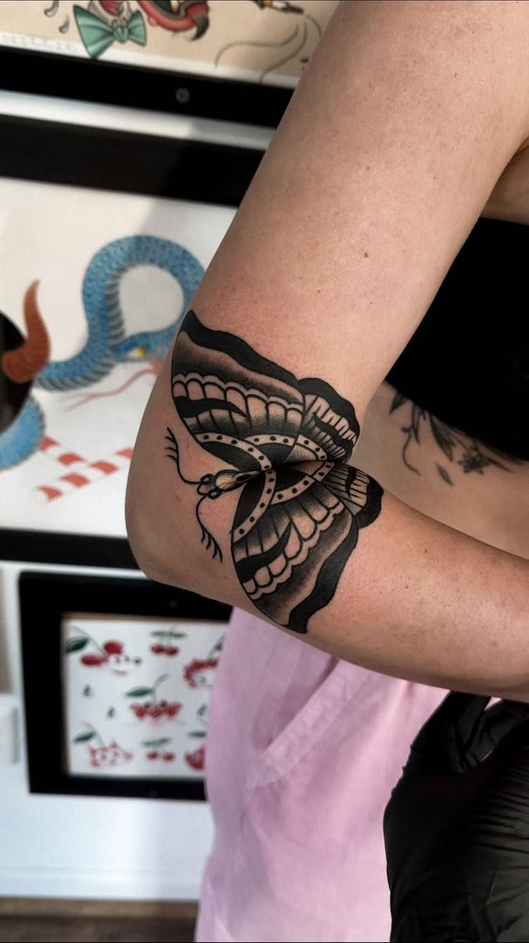 Moth tattoo in American traditional style on a person's inner elbow crease.