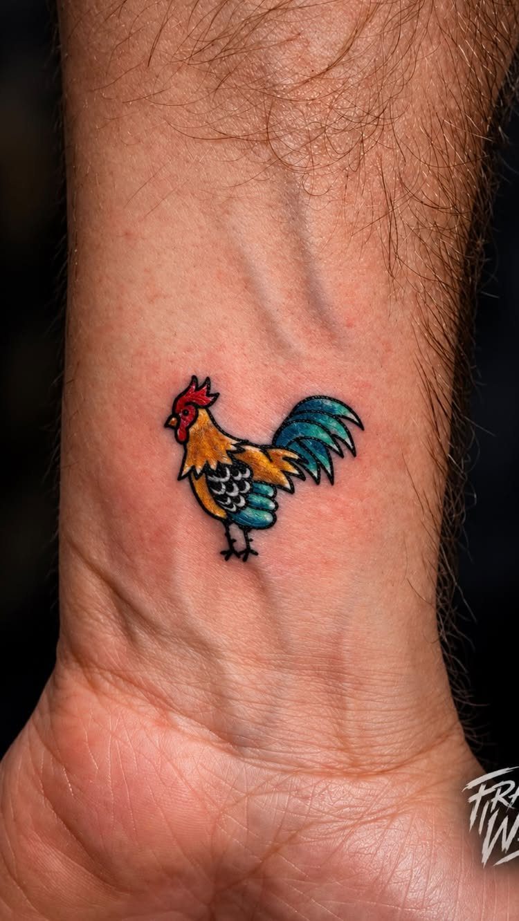 Rooster tattoo on a wrist with bold black outlines and bright colors.
