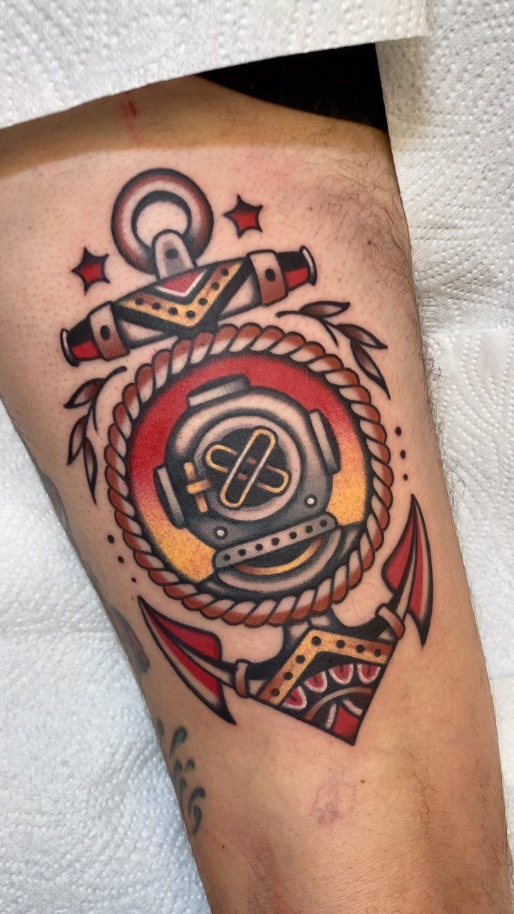 Traditional tattoo of a diving helmet and anchor on a man's arm.