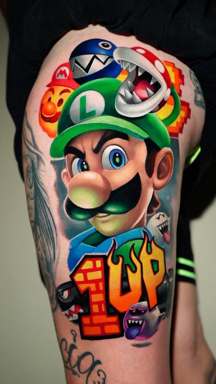 Colorful Mario franchise tattoo on a leg featuring Luigi and a 1UP mushroom.