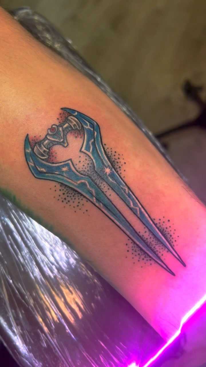 Blue energy sword tattoo from Halo on a person's forearm.