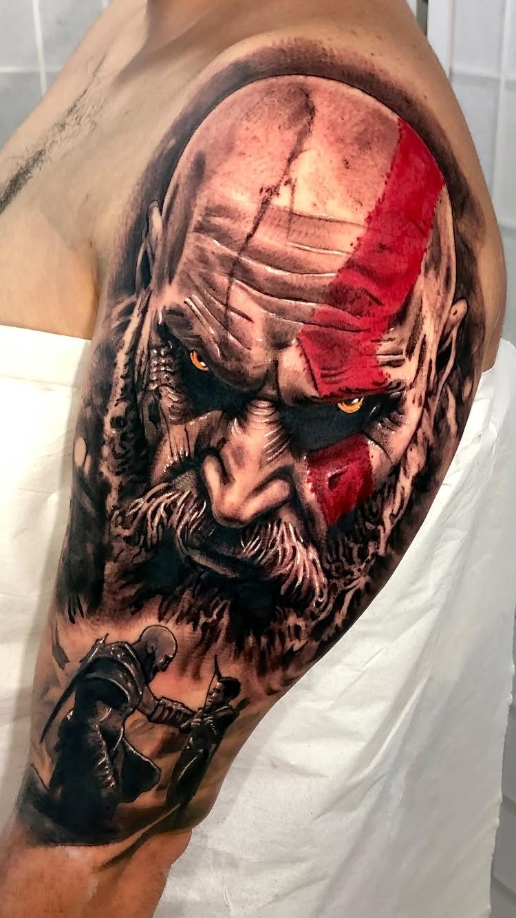 Kratos tattoo on an upper arm featuring a detailed portrait and a smaller scene.