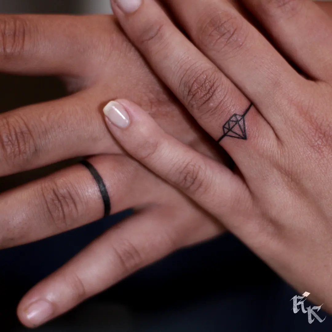 Two hands with black ink ring tattoos, one featuring a small diamond design.